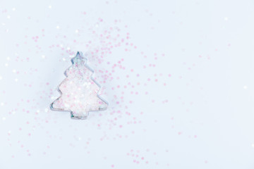 Flatlay with holiday tree cookie cutter and snowflake sprinkles on blue background. Holiday, Christmas and New Year concept. Cozy homey details