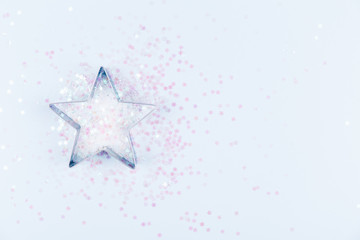 Flatlay with star cookie cutter and snowflake sprinkles on blue background. Holiday, Christmas and New Year concept. Cozy homey details