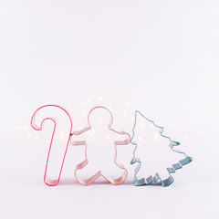 Obraz premium Multicolor cookie cutters on white sparkling background with bokeh lights. Holiday Christmas and New Year background