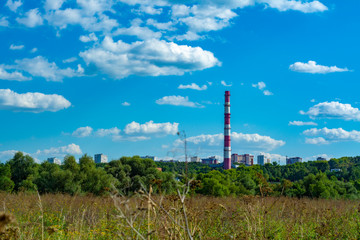 Fototapeta na wymiar Countryside panorama with forest and blue sky with clouds and factory chimney