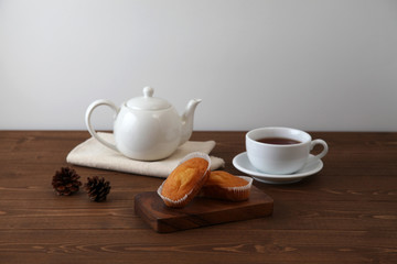 木のテーブルにのせた カップケーキ 紅茶 ティー ポット カップ