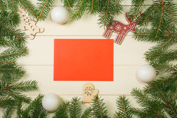 Fototapeta na wymiar Christmas tree frame branches, red envelope, balls and christmas toys on wooden background with copy space. Horizontal template for design