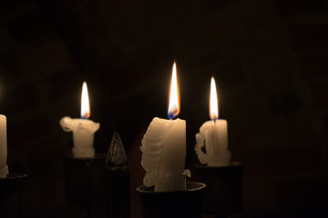Drei brennende weiße Kerzen auf dunklem Hintergrund