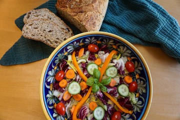 Mixed salad in decorative Italian pottery bowl and crusty whole grain bread, a healthy, delicious meal.