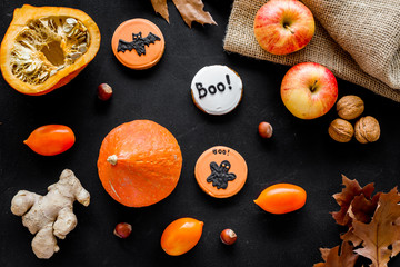 Halloween composition with autumn harvest as dried autumn leaves, pumpkin, apple and cute round hallooween badges with rats, ghousts, Boo text on black background top view pattern