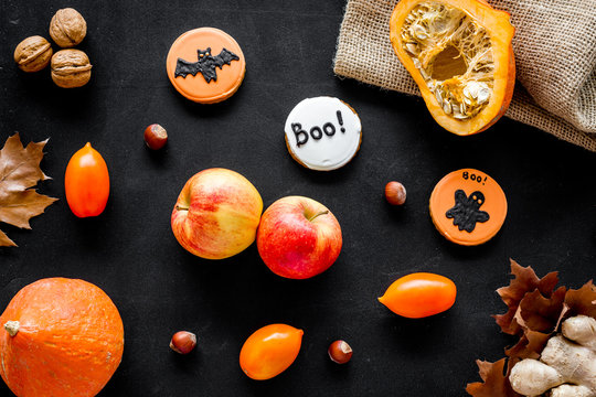 Halloween composition with autumn harvest as dried autumn leaves, pumpkin, apple and cute round hallooween badges with rats, ghousts, Boo text on black background top view pattern