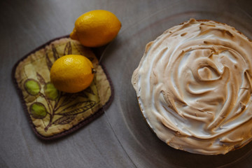 Lemon meringue pie on cutting board on brown wooden background