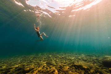 Woman Swimming Underwater In Crystal Clear Summer Lake