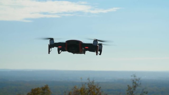 Concept of personal drones and aerial photography. Quadcopter flying overhead in cloudy blue sky