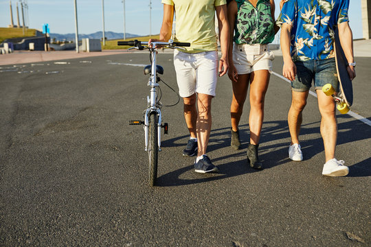 Unrecognizable friends walking on road.