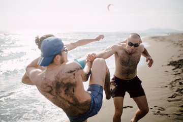 Friends having fun on the beach, wrestling