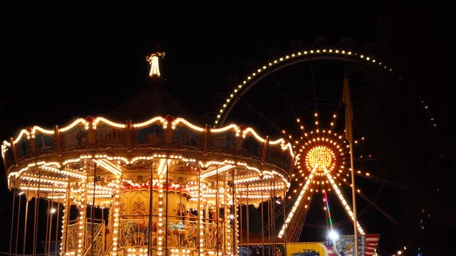 Wonderful slow motion view on vintage merry go round horse ride huge ferris wheel in colorful night light illumination