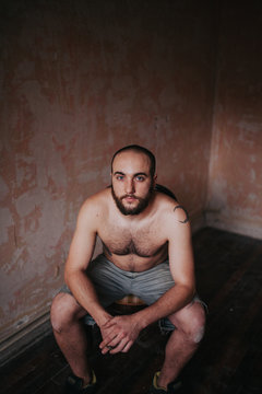 portrait of a bearded young man sitting on an empty room