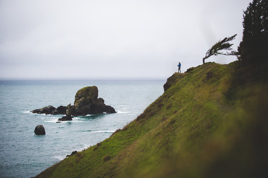 A young woman hiking on cliffs overlooking the Oregon Coast