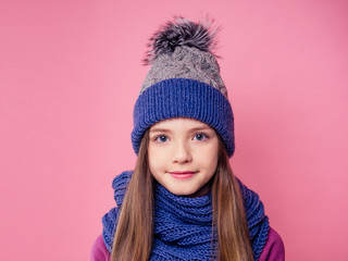 cute little girl in warm knitted colored hat on pink background in studio.Children winter clothes