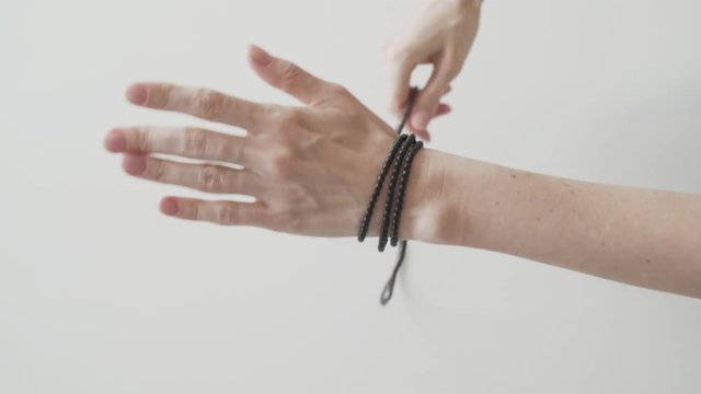 Woman ties a bracelet of long beads in her hand