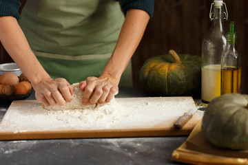 Women's hands knead the dough. Baking ingredients on wooden table