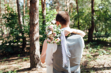 newlyweds hugging and standing in forest