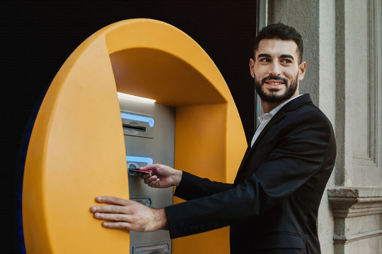 Young Happy Man Using ATM To Withdraw Cash