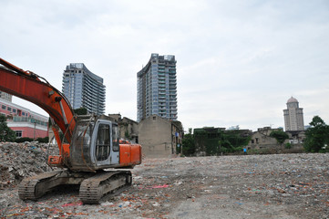 Fototapeta premium Digger in building site in Shanghai with skyscrapers behind