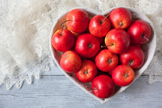 Red apples in a heart shape basket on the table