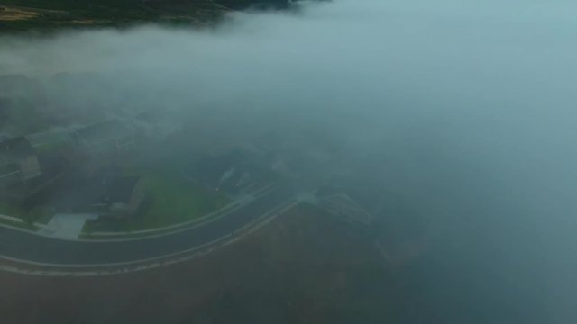 Aerial down into neighborhood with fog coming in.
