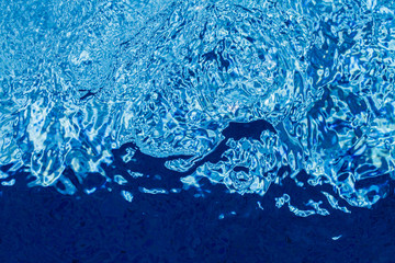 Bubbling water surface of a blue swimming pool, due to a jet stream.