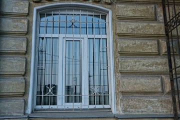window behind steel grate on gray concrete wall