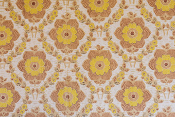 Close-up of a wall in an old rural house. Paper wallpaper with ornaments, large yellow flowers
