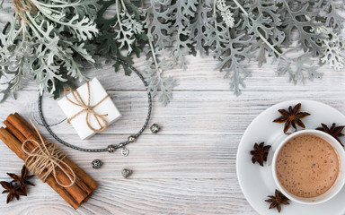 A gift for your beloved for any holiday - a fashionable jewellery bracelet with charms in a beautiful white box. Cineraria leaves, vanilla and cinnamon, a cup of coffee. Hygge Danish happiness. Autumn