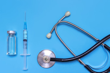 Syringe, vial and stethoscope on blue background , flat lay, top view