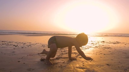 4K Slow motion - Two little brothersplaying and enjoying with teh sand in the beach at sunset