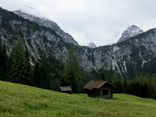 Green meadow, wooden cabin, cliff with waterfall, summit and clouds