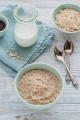 Oatmeal porridge bowl on the white wooden background.
