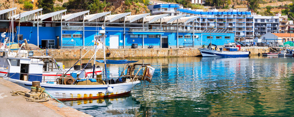 Fishing boats and yachts moored at pier in port Blanes. Fishermen unload catch of sea fish, oysters, squid, sea delicacies. Fish auction for wholesalers and restaurants. Blanes, Spain, Costa Brava