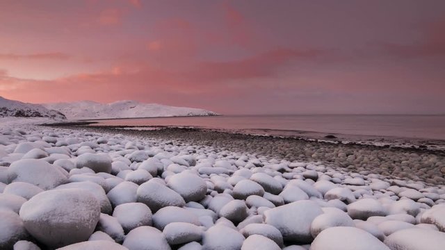 Sunset on the snow-covered shore of the Barents Sea