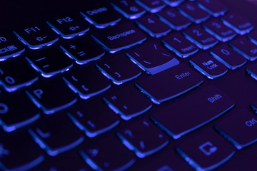 Blue backlit laptop keyboard, hacking and blockchain concept