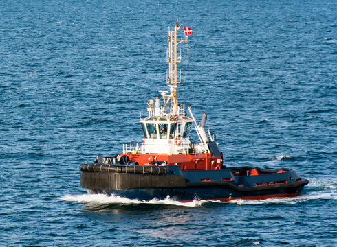 A tugboat with a Danish flag navigates on the sea