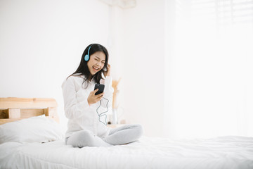 Portrait of beautiful woman in morning listening music sitting on bed at home. Portrait of beautiful woman