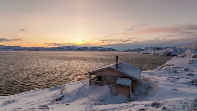 Cottage on the shore of the Arctic Ocean at dawn in winter