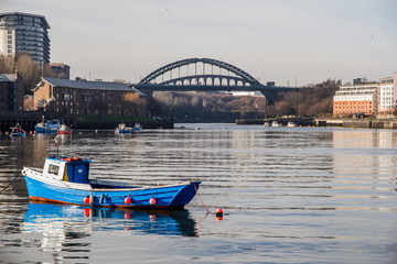View of Sunderland’s sea fishing harbour with boatd reflecting in the still water and the iconic Wearmouth Bridge in the background