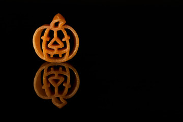 Culinary Halloween. Italian pasta meal shaped like an orange pumpkin on a black background
