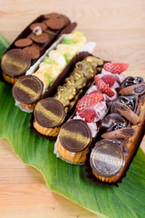 Appetizing eclairs on a wooden table and decorated with leaves. Eclairs on the table. Sweets.