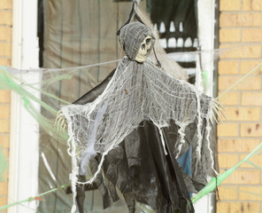 Halloween skeleton decoration dressed in black robe with white shawl blocking access across doorway
