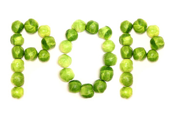 The word 'pop' is spelled out with brussel sprouts on a white background to provide a light hearted...