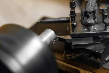 turning a rotating workpiece on a old manual metalworking lathe, focus on the tip of the tool bit
