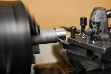 turning a rotating workpiece on a old manual metalworking lathe, focus on the tip of the tool bit
