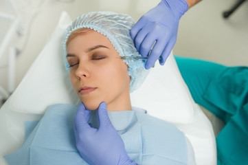 lateral view of the preparation for augmentation procedure on a young woman done by a cosmetologist...