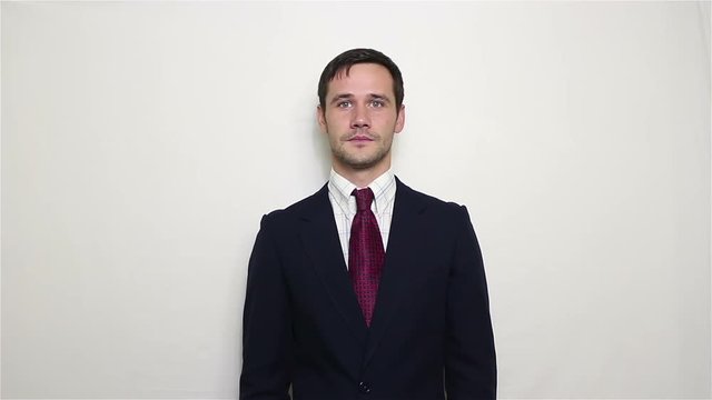 Young handsome businessman in a blue suit first greets the partners waving his hand, and then bids farewell to them.Portrait on a white background.