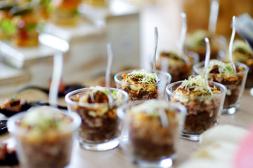 Fresh and delicious vegetable and pork salad served in mini glasses on a party or wedding reception.